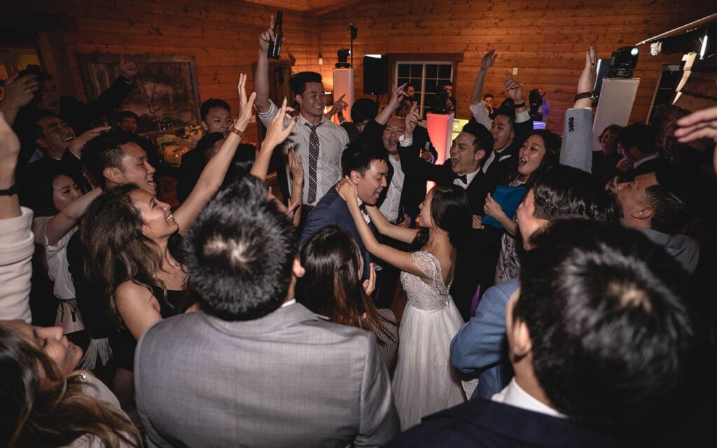 A newlywed couple surrounded by joyful friends celebrating at a lively party.